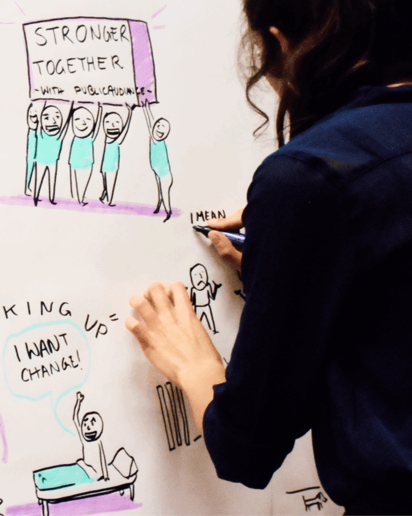 Veronika Götz beim Graphic Recording – King up! I want Change Fotografie von Veronika Götz beim Graphic Recording in Schwarz, Blau und Violett, zeigt den Text „King up! I want Change“.